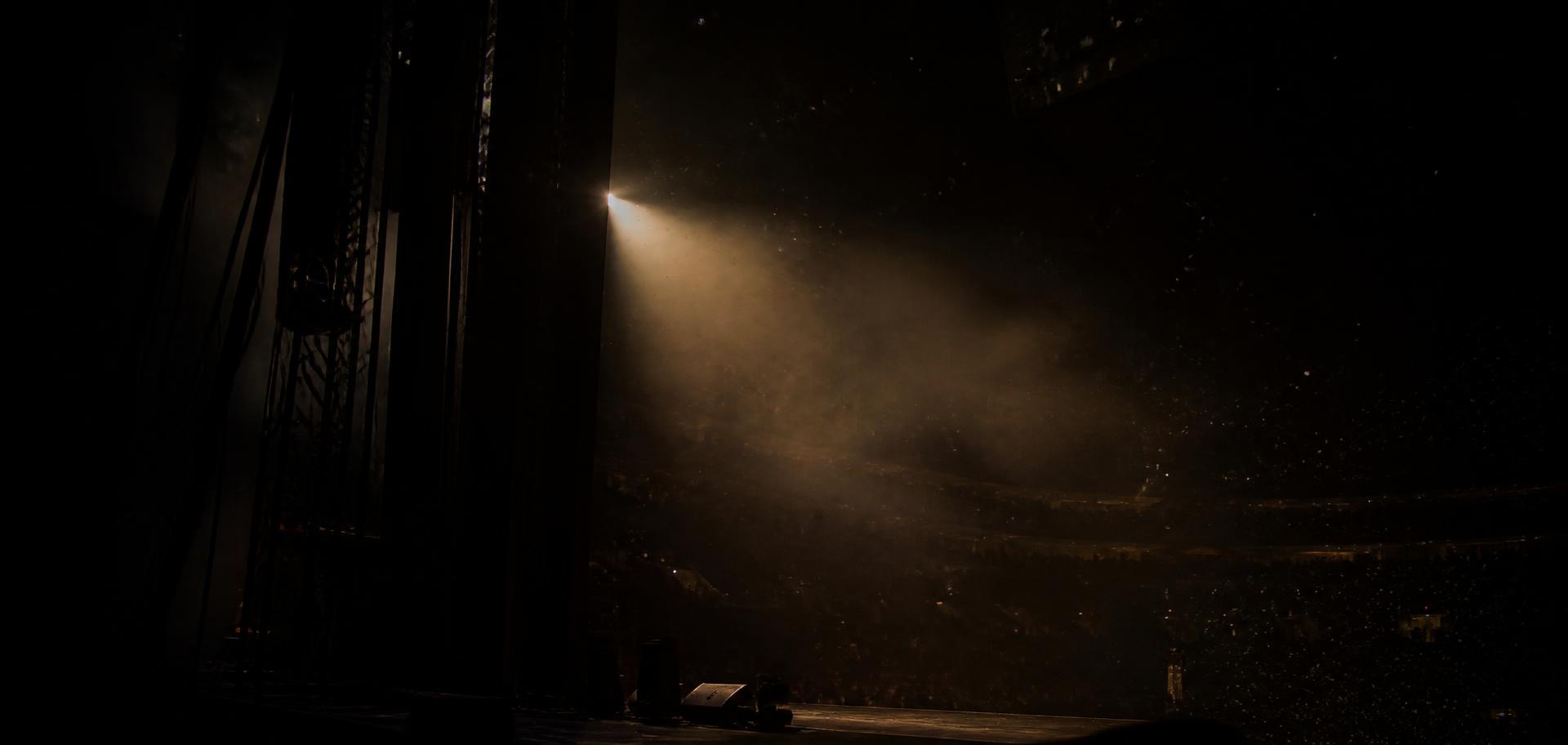 Dark arena stage lit by a single warm spotlight